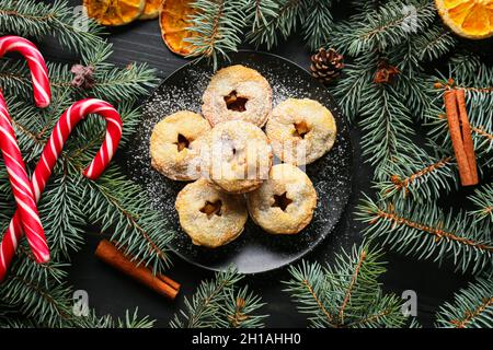 Piatto con gustosi torte di mince e decorazioni natalizie su sfondo scuro Foto Stock