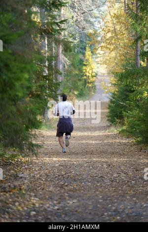 Atleta uomo jogging in autunno foresta. Atleta maschile prima di correre maratona nel parco Foto Stock