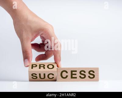 Processo per il concetto di successo. Mano che gira il blocco di cubo di legno per cambiare le parole, da processo a successo isolato su sfondo bianco. Crescita aziendale Foto Stock