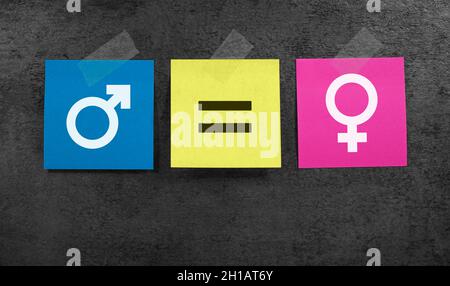 Concetto di uguaglianza di genere e parità di genere con icona maschile e femminile e simbolo del segno di uguale su note di carta blu e rosa su sfondo grigio. Foto Stock