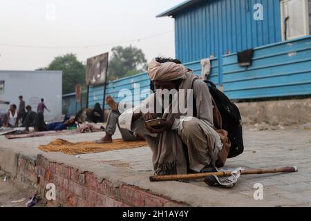 New Delhi, India. 16 ottobre 2021. Un uomo senza tetto mangia cibo distribuito da volontari lungo la strada a Nuova Delhi. L'India è scivolata alla 101a posizione tra 116 paesi nel Global Hunger Index (GHI) 2021 dalla sua graduatoria di 94 un anno fa Credit: SOPA Images Limited/Alamy Live News Foto Stock