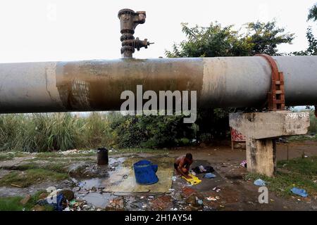 New Delhi, India. 16 ottobre 2021. Un uomo senza tetto vede i vestiti di lavaggio sotto un gasdotto rotto dell'acqua a Nuova Delhi. L'India è scivolata alla 101a posizione tra 116 paesi nel Global Hunger Index (GHI) 2021 dalla sua graduatoria di 94 un anno fa Credit: SOPA Images Limited/Alamy Live News Foto Stock