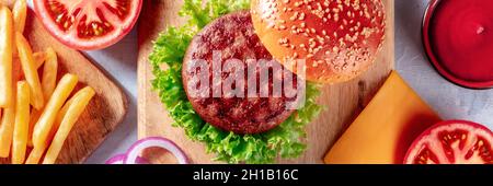 Panorama degli ingredienti del Burger, girato dall'alto. Hamburger di manzo, patatine fritte, insalata verde, ketchup, top shot Foto Stock