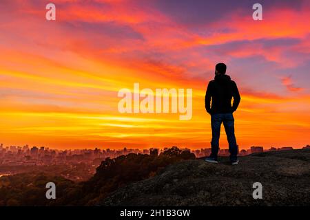 Giovane uomo in piedi in montagna all'alba e godendo di vista della natura. Foto Stock