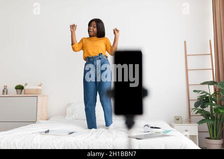 Black Female Blogger fare video su smartphone avere divertimento indoor Foto Stock