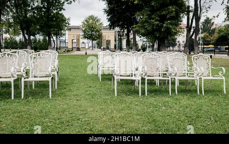 File di sedie bianche vuote su un prato prima di un matrimonio o una cerimonia Foto Stock