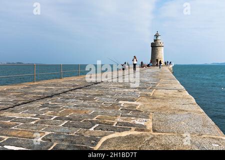 dh Castle Breakwater Lighthouse ST PETER PORT GUERNSEY Woman camminando lungo i moli molo del porto in pietra di granito Foto Stock