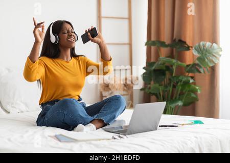 African Lady ascoltare musica indossando cuffie che squilla in camera da letto Foto Stock