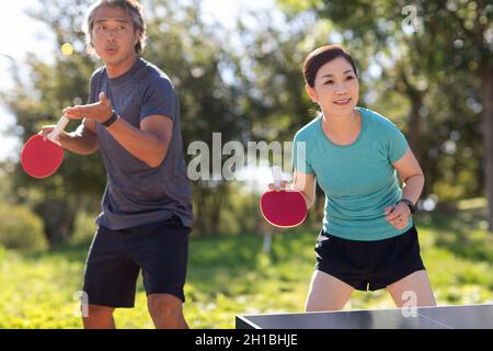 Coppia matura felice giocare a ping pong all'aperto Foto Stock
