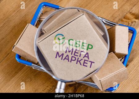 Foto modificata del logo SberMegaMarket su una scatola sotto la lente d'ingrandimento nel carrello. Foto Stock