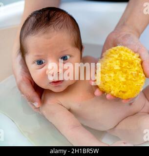 Primo bagno di bambino neonato boy.The mamma lava il bambino con spugna  naturale Foto stock - Alamy