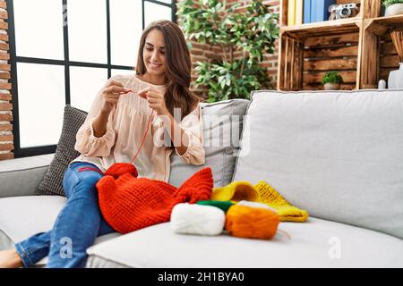 Giovane ispanica sorridente fidata tessendo in finisce a casa Foto Stock