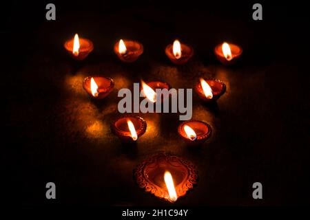 Gruppo di diya decorati su sfondo nero durante Diwali Foto Stock