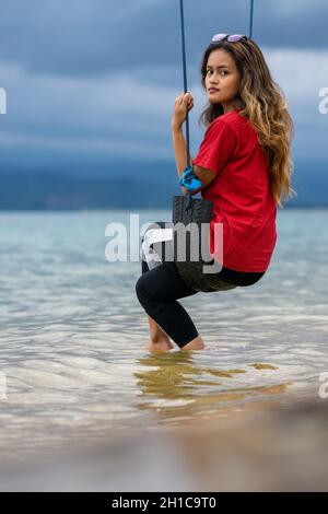 Colpo verticale di donna indonesiana che oscilla su una riva a Sulawesi, Isole Toghian Foto Stock