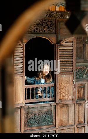 Colpo verticale di una donna indonesiana in posa in Tongkonan case tradizionali nel villaggio di Palava Foto Stock