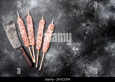 Insaccati crudi di manzo e agnello di carne kebabs set, su sfondo nero tavolo di pietra scura, vista dall'alto piatto, con spazio per la copia del testo Foto Stock