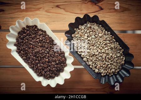 Caffè in grani crudo e torrefatto fragrante e aromatico in contenitori sul tavolo. Caffè, bevande, produzione Foto Stock