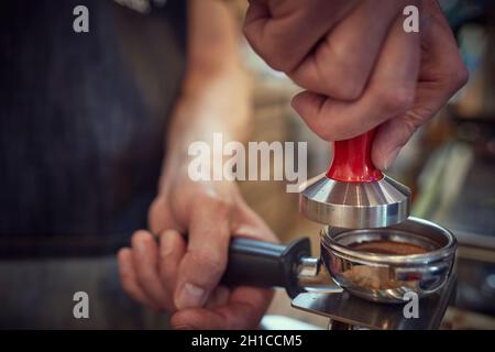 Una misura di caffè macinato fragrante e aromatico preparato per l'espresso dal barman. Caffè, bevande, bar Foto Stock