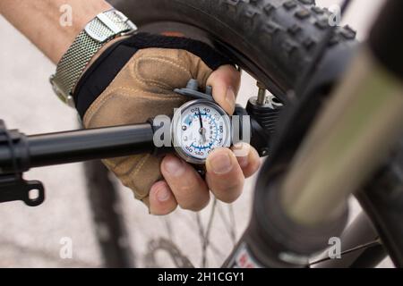 uomo che controlla la pressione degli pneumatici di e bike, gonfiando l'aria con la pompa a mano Foto Stock