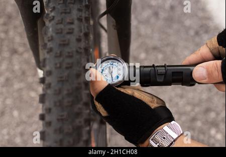 uomo che controlla la pressione degli pneumatici di e bike, gonfiando l'aria con la pompa a mano Foto Stock