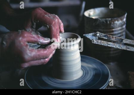 Primo piano delle mani dell'uomo gettando una pentola sulla ruota di un vasaio. Foto Stock