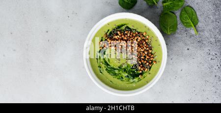 Frullati utili da spinaci con fiocchi di grano saraceno in ciotole in ceramica su sfondo grigio tavolo in cemento. Messa a fuoco selettiva. Vista dall'alto. Spazio di copia. Foto Stock