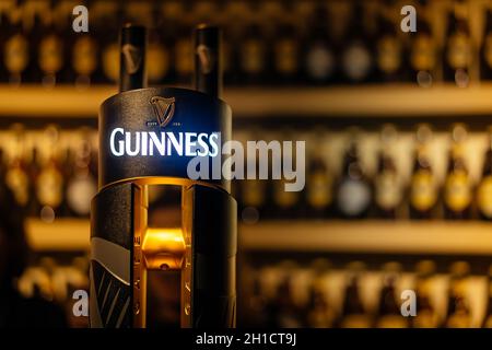 Dublino, Irlanda, dicembre 2017 Focus selettivo sul Guinness tap con pareti sfocate di bottiglie. Guinness è l'iconica birra irlandese Foto Stock