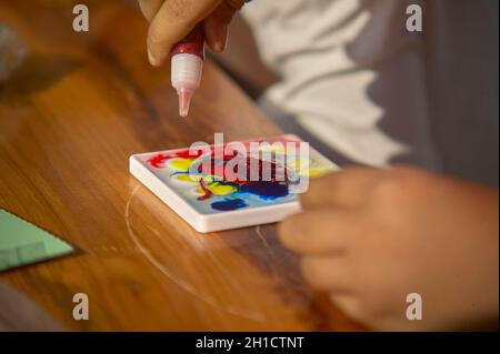 Tempera colorata utilizzata da un bambino durante le sue attività di apprendimento Foto Stock