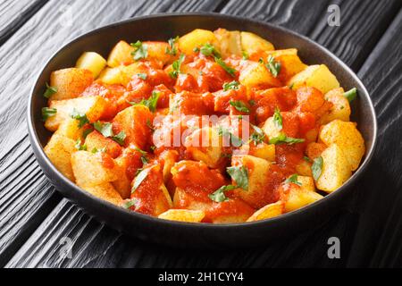 Patatas Bravas ricetta patate fritte con salsa di vas primo piano nel piatto sul tavolo. Orizzontale Foto Stock