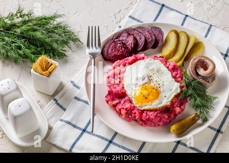 labskaus, carne di manzo, purè di patate con barbabietole ricoperte di uova fritte, barbabietole affettate, sottaceti e rollmops, sottaceto, aringa arrotolata Foto Stock