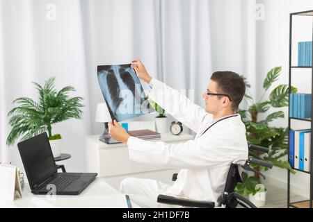 In un ufficio ospedaliero, un medico pulmonologey controlla la radiografia del polmone di un paziente. Foto Stock