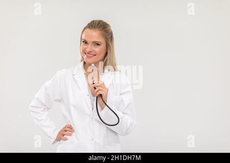 Sorridente medico in piedi tenendo uno stetoscopio di fronte a lei. Foto Stock