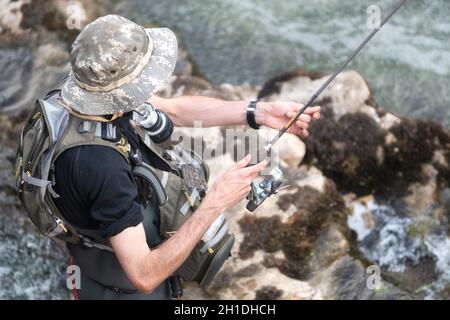 L'uomo la pesca nel fiume. fisher in acqua. fisherman Visualizza tecnica di pesca l'uso. Asta. hobby e attività sportiva . Foto Stock