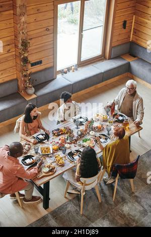 Vista ad alto angolo della famiglia che parla l'un l'altro durante la cena al tavolo da pranzo di casa Foto Stock