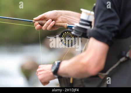Uomo di Pesca a Mosca Report di pesca con mulinello e l'asta. Sport fly fisher uomo vicino a bobina . Foto Stock