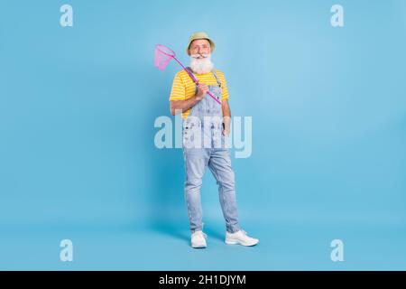Foto a tutta lunghezza di uomo anziano felice sorriso positivo tenere rete cattura insetto isolato su sfondo blu Foto Stock