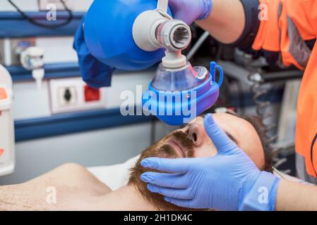 Covid-19 insufficienza respiratoria. Medico d'urgenza usando maschera Ambu sacco su un paziente con polmonite a causa di infezione da Coronavirus, per ventilazione artificiale Foto Stock