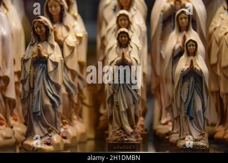 Lourdes, Francia - 9 Ott 2021: Statue figurine della Vergine Maria in vendita presso un negozio di souvenir turistico a Lourdes, Francia Foto Stock