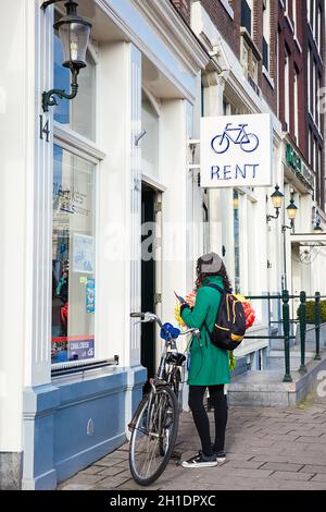 AMSTERDAM, PAESI BASSI - Marzo 2018: giovane donna a un noleggio bike shop nel vecchio quartiere centrale di Amsterdam Foto Stock