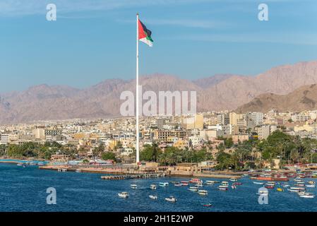 Aqaba Giordania - 6 Novembre 2017: Cityscape di Aqaba e Bandiera della Giordania sventolare sopra la città. Bandiera araba di Revolt-Sixth più alto pennone nel mondo Foto Stock