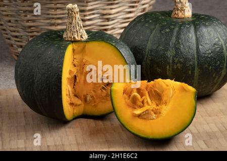 Zucca Kabocha verde fresca intera e un taglio da vicino su una tavola da taglio Foto Stock