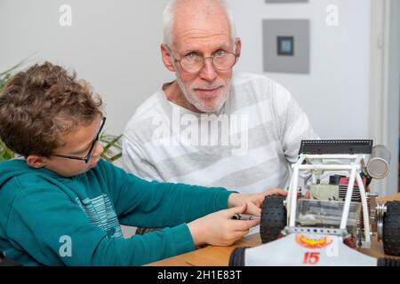 nonno e figlio ragazzino che riparano un modello di auto radiocomandata Foto Stock