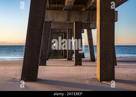 La sottostruttura del molo di pesca del Gulf state Park all'alba crea modelli interessanti sulla spiaggia di Gulf Shores, Alabama Foto Stock