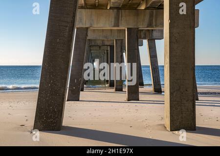 La sottostruttura del molo di pesca del Gulf state Park all'alba crea modelli interessanti sulla spiaggia di Gulf Shores, Alabama Foto Stock