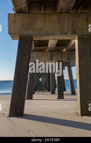 La sottostruttura del molo di pesca del Gulf state Park all'alba crea modelli interessanti sulla spiaggia di Gulf Shores, Alabama Foto Stock
