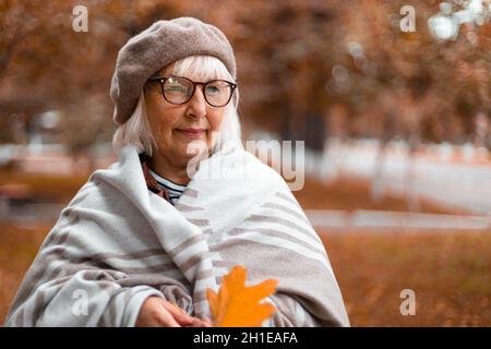 Stagione autunnale. Donna anziana che cammina nel parco in autunno Foto Stock