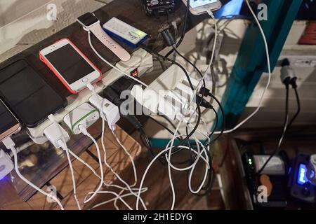 Nuqui, Choco, Colombia - circa 2019: Un sacco di caricabatterie per dispositivi aggrovigliati in un angolo affollato. L'elettricità è disponibile solo periodicamente nella villa Foto Stock