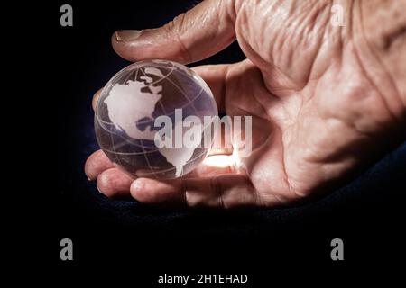 Mano con mondo trasparente con mappa delle Americhe in primo piano Foto Stock