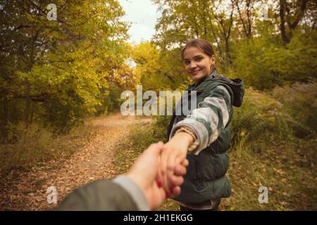 Ritratto corto di bella giovane donna che tiene la mano maschile. Escursioni. Romantica attività autunnale Foto Stock