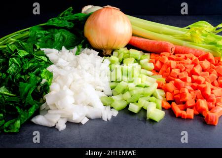 Spinaci tritati con cipolle a dadini, sedano e carote: Verdure tritate verdure intere sullo sfondo Foto Stock